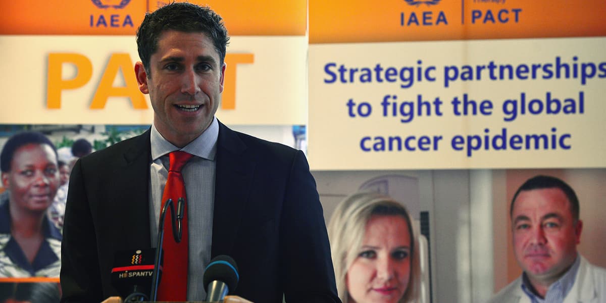 A man in a suit giving a speech at an initiative to combat cancer
